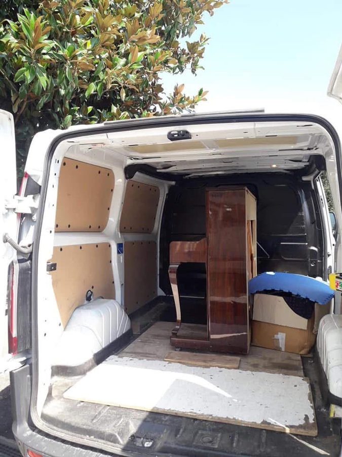 Pianoforte verticale nel vano di carico del furgone, circondato da teli e scatoloni
