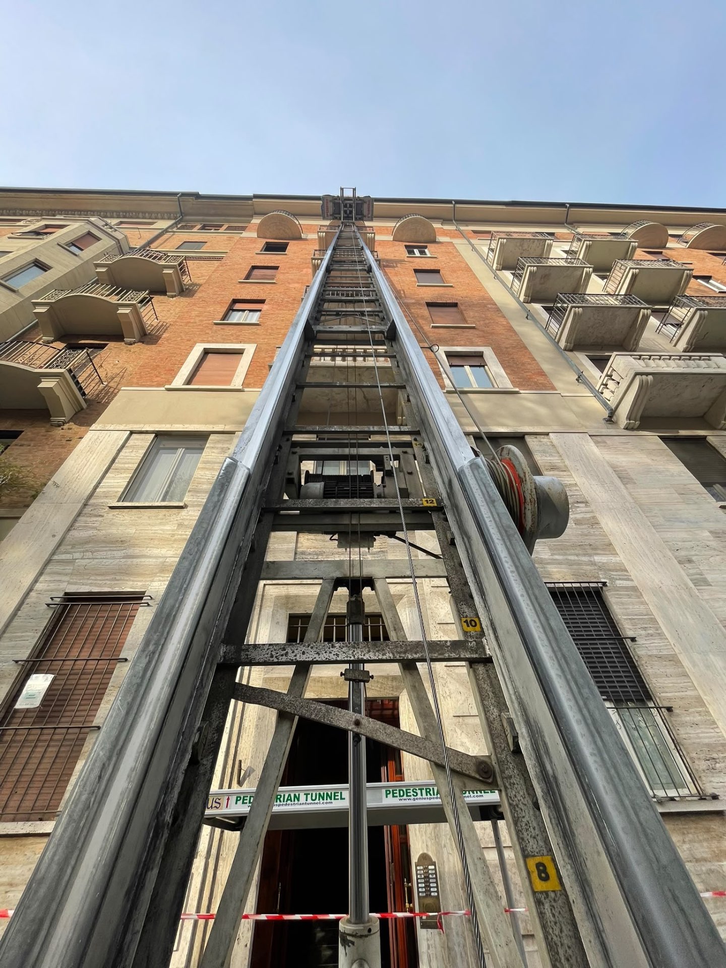 Autoscala fotografata dal basso mentre sale lungo la facciata verso il cielo