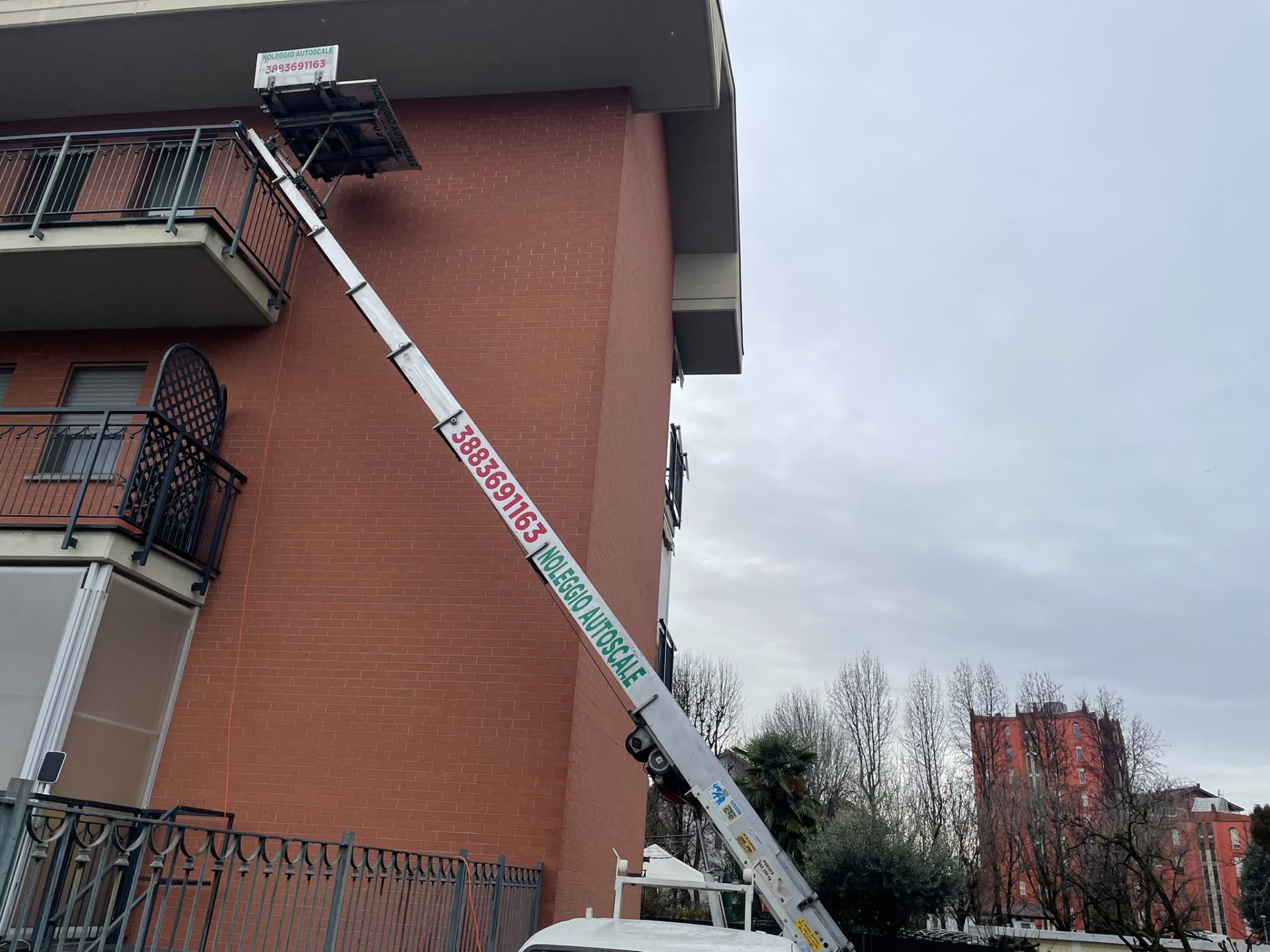 Autoscala che raggiunge il balcone all’ultimo piano di un palazzo in mattoni