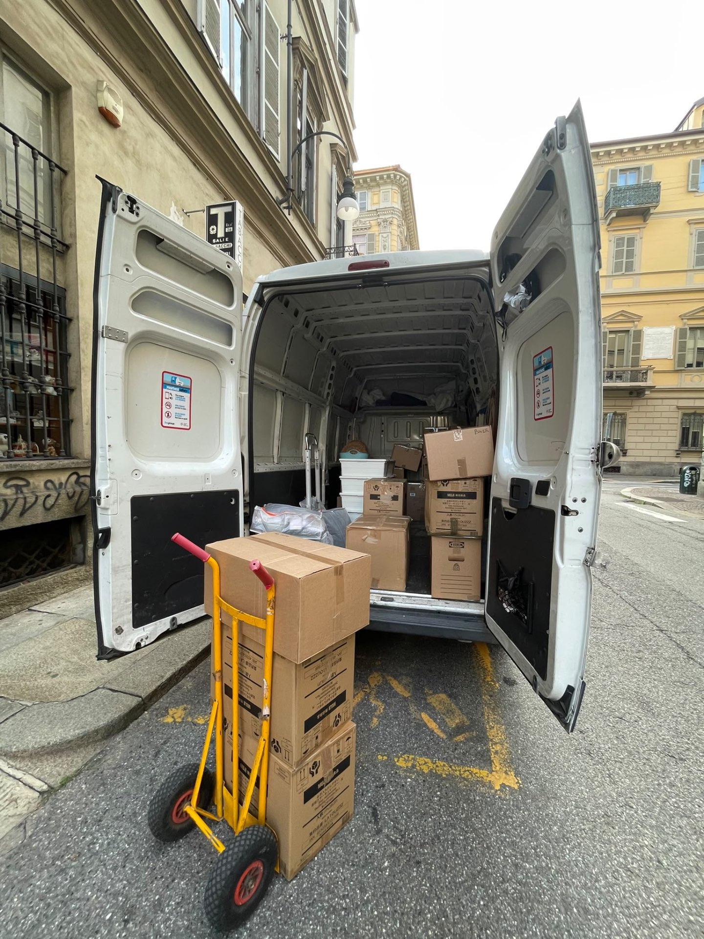 Furgone aperto con scatole e carrello da trasloco in una via di Torino